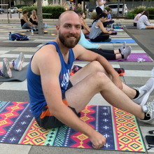 Load image into Gallery viewer, white male sitting on geometric yoga mat 
